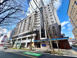 a tall building on a city street with trees at Hotel The Centre Utsunomiya in Utsunomiya