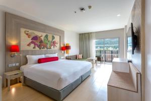 a bedroom with a large bed and a balcony at Ramada by Wyndham Phuket Deevana in Patong Beach