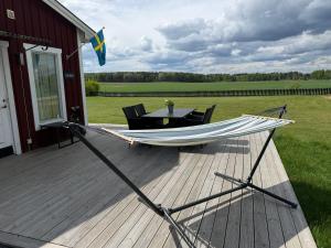 a hammock on a deck next to a table at Swedish countryside jacuzzi and pool! in Uppsala