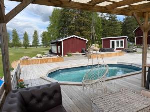 a patio with a swing and a swimming pool at Swedish countryside jacuzzi and pool! in Uppsala