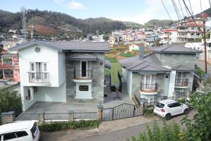a white house with cars parked in front of it at Two Seas Residence - Boutique Residences in Ooty