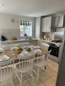 a kitchen with a wooden table and white chairs at Waters Reach in Abersoch