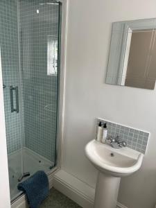 a white bathroom with a sink and a shower at Waters Reach in Abersoch