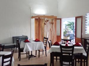a dining room with tables and chairs with red napkins at Coral Quays Resort in Luganville +14 photos