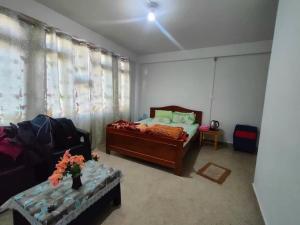 a bedroom with a bed and a couch and a window at Salena Homestay in Cherrapunji