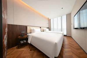 a bedroom with a large white bed and a television at 上海安鉌蓓斯特酒店国家会展中心虹桥机场店 in Hongqiao Intl
