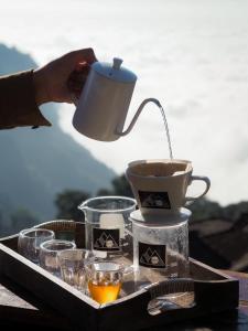 a person is pouring coffee into a tray with glasses at ผาฮี้แลนด์โฮมสเตย์ in Mae Sai +11 photos