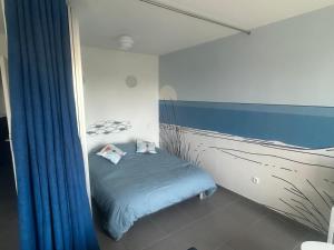 a small bedroom with a bed with blue sheets at Charmant studio vue dégagée à 300m de la plage in Dunkerque