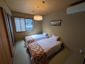 a bedroom with two beds and a window at YADOYA Suzume in Tokyo