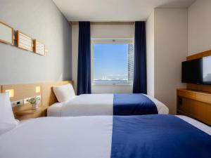a hotel room with two beds and a television at Yokohama Sakuragicho Washington Hotel in Yokohama