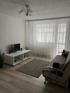 a white living room with a bed and a tv at Margo Apartament cu 2 camere in Târgu Jiu
