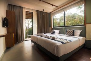 a bedroom with a large bed and a large window at Kayn by spynora in Vythiri +86 photos