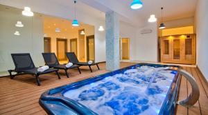 a jacuzzi tub in a room with two chairs at Villa Ida - Indoor Heated Pool, Sauna, Games Room and Gym in Mellieħa