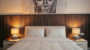 a bedroom with a bed with two lamps and a portrait at Villa Ida - Indoor Heated Pool, Sauna, Games Room and Gym in Mellieħa