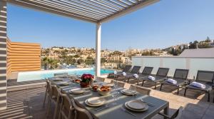 a table and chairs on a balcony with a pool at Villa Ida - Indoor Heated Pool, Sauna, Games Room and Gym in Mellieħa +48 photos