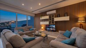 a living room with two couches and a television at Villa Ida - Indoor Heated Pool, Sauna, Games Room and Gym in Mellieħa
