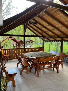 a picnic table and chairs on a patio with a roof at Poteca Ursului in Arefu