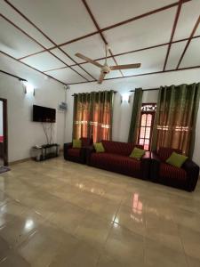 a living room with couches and a flat screen tv at Luckwin Guest in Anuradhapura
