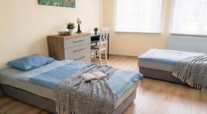 a bedroom with two beds and a desk with a chair at Apartament Słoneczny Węgorzewo 74m2 in Węgorzewo