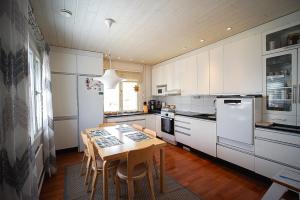a kitchen with a wooden table and white appliances at Villa Golden Haven in Rovaniemi