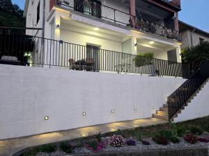a house with a white wall and a fence at Apartmani Nikolić "Na pjeni od mora" in Tivat