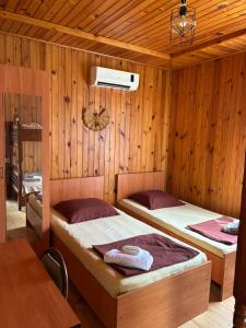 two beds in a room with wooden walls at Wooden Cottage in Makhinjauri