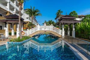 a swimming pool in a resort with a white fence at Kata Sea Breeze Resort - SHA Plus in Kata Beach