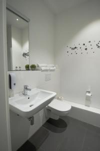 a white bathroom with a sink and a toilet at MyRoom - Top Munich Serviced Apartments in Munich +26 photos