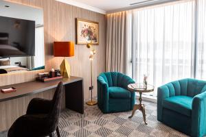 a hotel room with two chairs and a table and a bed at Sky Airport Hotel in Cluj-Napoca