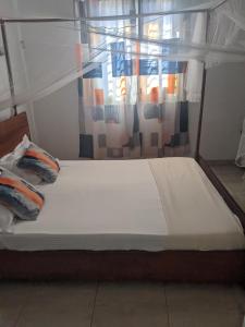 a bed with two pillows on it with a window at Appartement VIDA 1 in Mahajanga