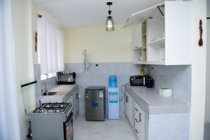 a kitchen with white counters and a stove top oven at comfystdngong in Nairobi +28 photos