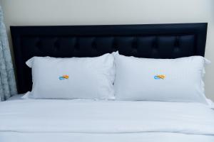 a bed with white pillows and a black headboard at comfystdngong in Nairobi