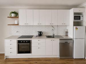 a kitchen with white cabinets and a sink and a refrigerator at West Beach Lagoon 123 - Location & Views!!! in Perth