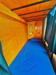 a bed in a small room with a box sign at ak Hostel selayar in Benteng