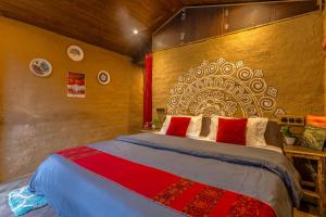 a bedroom with a large bed with red pillows at Monkey Mud House and Glamps, Bir in Bīr