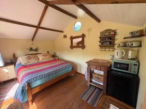 a bedroom with a bed and a microwave in it at Tyluna Cornish Glamping Cabin in Praze an Beeble