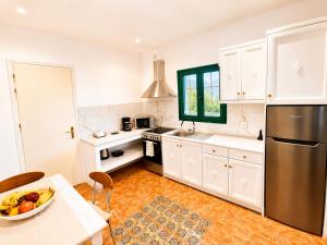 a kitchen with white cabinets and a bowl of fruit on a table at Ostria Beach House in Órmos Marathokámpou
