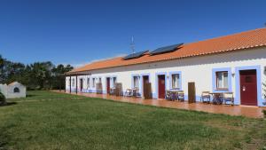 a building with tables and chairs outside of it at O Monte da Estrada in Zambujeira do Mar