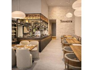 a restaurant with wooden tables and a counter with two chefs at Sunday Residence Split in Split