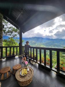 a boy standing on a balcony looking out at the mountains at Sapa mến khách sapa jade hill in Lao Cai