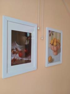 two pictures on a wall with a bowl of fruit at sicsac inn in Jorhat
