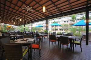 a restaurant with tables and chairs and blue umbrellas at Kata Sea Breeze Resort - SHA Plus in Kata Beach