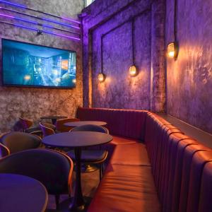 a bar with tables and chairs and a tv on the wall at Cinematique Boutique Cinema Hotel in Bangkok