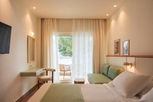a hotel room with a bed and a chair and a window at Akrotiri Beach Resort & Spa - Adult Friendly in Paleokastritsa +65 photos