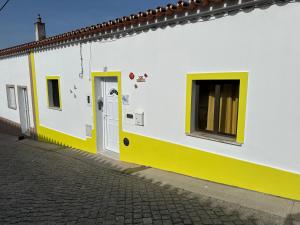 a white and yellow building with a door at Ar Doce in Portel