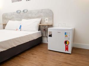 a room with a small refrigerator next to a bed at ibis budget Sorocaba in Sorocaba