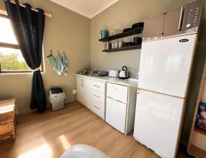 a kitchen with a white refrigerator and white cabinets at At the Indi in Struisbaai