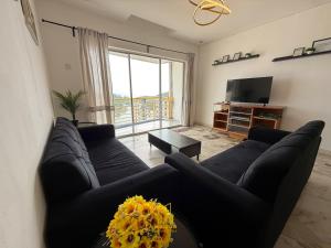a living room with a black couch and a tv at BayView Suites Port Dickson By MAISON in Port Dickson