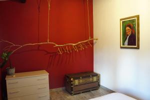 a bedroom with a red wall and a dresser and a painting at Podere Al Covo - House, Garden & Vineyard - Alghero in Alghero +32 photos