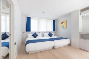 a white and blue bedroom with two beds at RHUMB LINE Tokyo in Tokyo